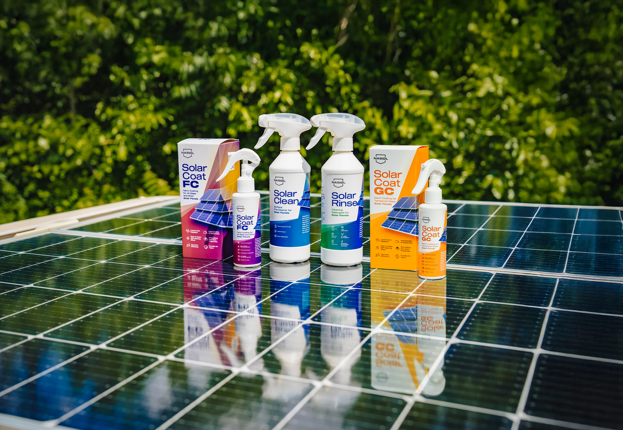 Assorted cleaning products for solar panels lined up on a row of solar panels outdoors on a sunny day.