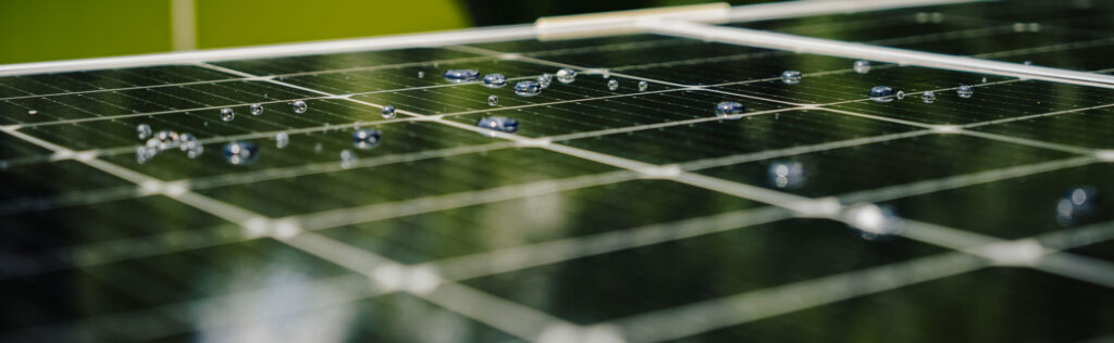 Close-up of solar panels with droplets of water on the cells under sunlight.